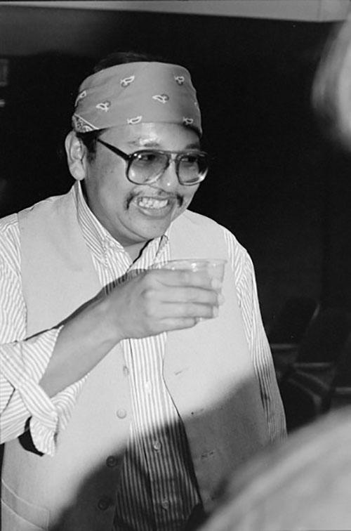 Poet and novelist Ray A. Young Bear smiles and holds a cup in the University of Arizona Modern Languages Auditorium at his reading for the Poetry Center's Spring 1993 Reading and Lecture Series. 